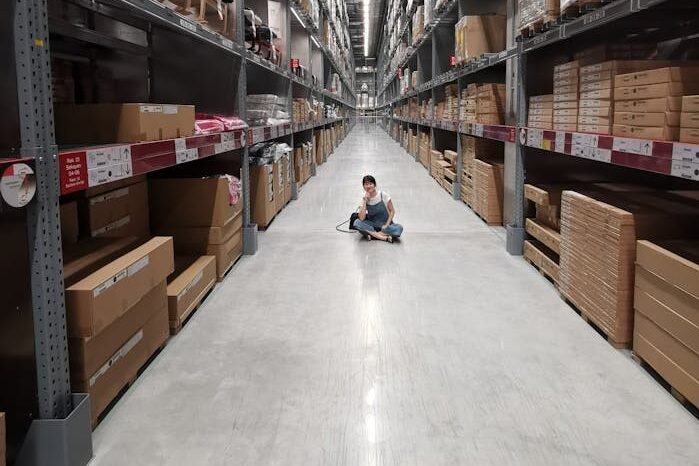 Person Sitting on Ground Between Brown Cardboard Boxes